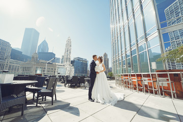 Elegant bride in a white dress and veil. Handsome groom in a blue suit. Couple in a big town