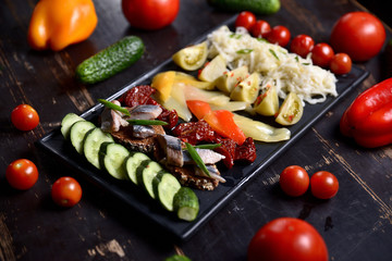 set of pickled vegetables and fish on a dark plate