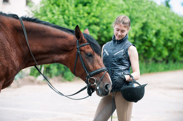Obraz premium Young teenage girl tenderly looking at her favorite red horse