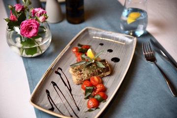 fried piece of fish with tomato and lemon on a plate