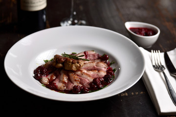 fried duck meat with berry sauce on a white plate