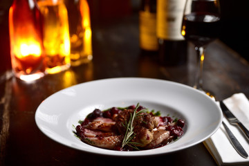fried duck meat with berry sauce on a white plate