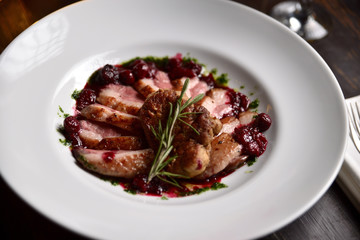 fried duck meat with berry sauce on a white plate