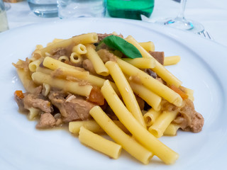 Italian short pasta dish with tuna Genoese, carrots onions and basil leaf