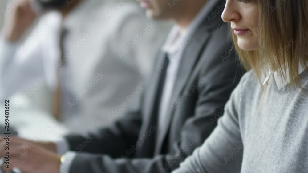Poster tilt up of businessman and businesswoman typing on laptops at office desk and discussing something w