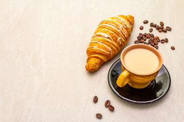 A cup of fresh coffee with croissant. The concept on a stone background, copy space.