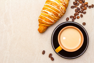 A cup of fresh coffee with croissant. The concept on a stone background, top view, copy space, close up.