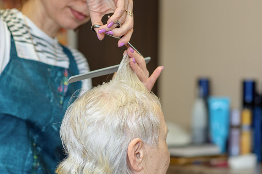 Haircut for the elderly. The process of cutting grandma's in the hair salon.