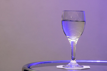water in glass on the table with purple light