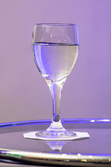 water in glass on the table with purple light