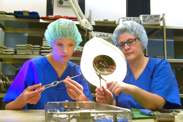 Two women work in a hospital as medical hygiene  technicians. They are dressed in special medical ...