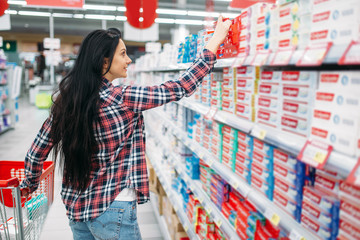Young woman buying toothpaste in supermarket
