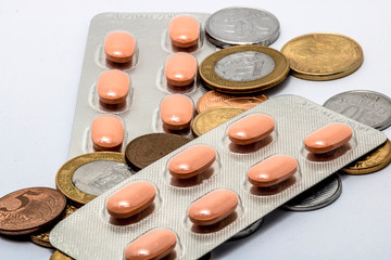 Pills in aluminum blister pack and brazilian real coins isolated on white
