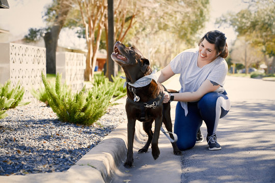 Smiling woman with dog crouching outdoors