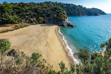 une grande plage déserte et ensoleillée entre deux côtes rocheuses