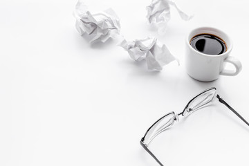 blogger office desk with glasses, coffee and paper balls on white background copyspace