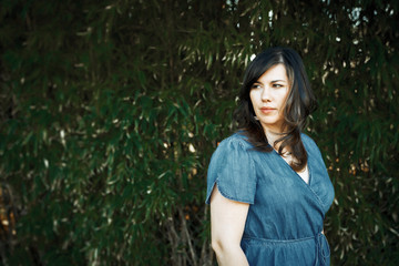 Brunette woman standing against tree