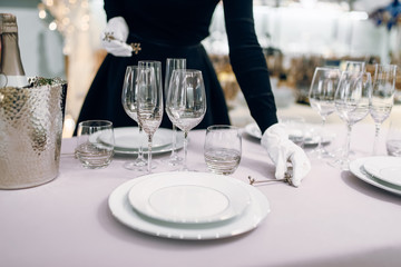 Waitress in gloves puts the knife, table setting