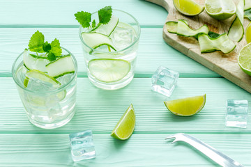 cold water with ice, cucumber and lime juice for summer healthy drink on mint green wooden background