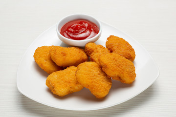 golden pieces of deep-fried cheese laid out on a white plate, next to a red sauce in a bowl