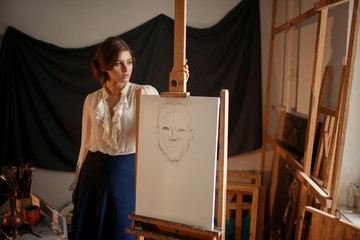 Cute female artist drawing in studio