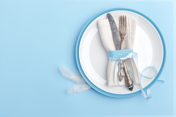 Elegant stylish table setting. Knife and fork on a napkin on a plate on a blue background.