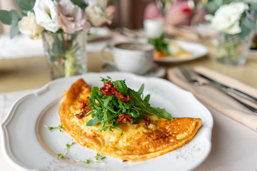 Breakfast. Frittata - italian omelet. Omelette with tomatoes, arugula and soft cheese. Coffee and other dishes on the table in the restaurant