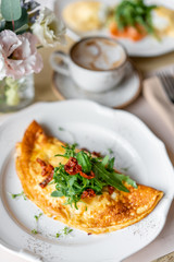 Breakfast. Frittata - italian omelet. Omelette with tomatoes, arugula and soft cheese. Coffee and other dishes on the table in the restaurant