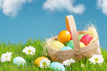 Fototapeta premium Basket with painted Easter eggs on green grass. Easter holiday concept.