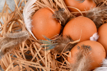 Many eggs lie on the background of hay, top view.