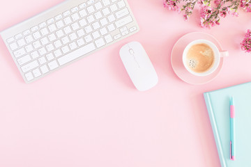 Office pink table, notepad, keyboard, flowers, coffee, notebook, stationery on pink background....