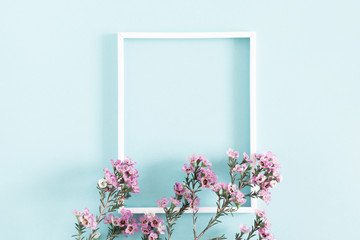 Beautiful flowers composition. Blank frame for text, pink flowers, on pastel blue background. Valentines Day, Easter, Birthday, Mother's day. Flat lay, top view, copy space