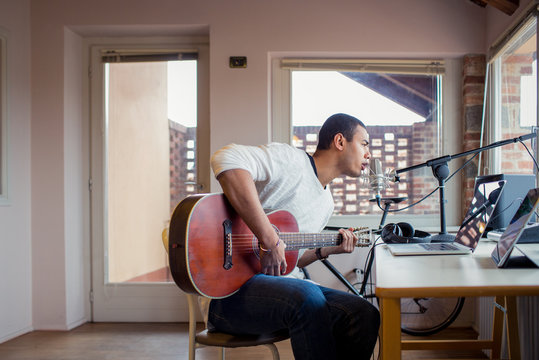 Man singing with guitar while sitting in studio