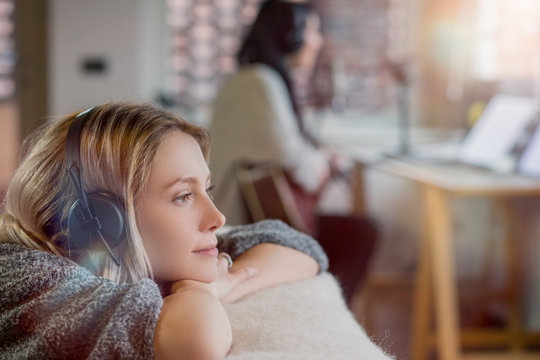 Young woman with bleached hair listening to music while lying indoors