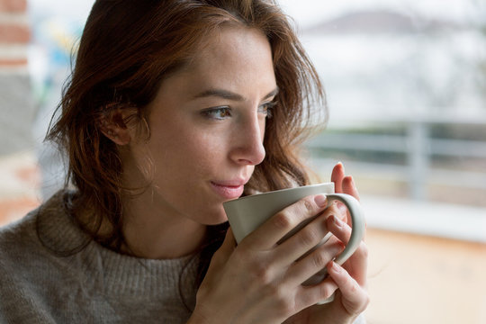 Close up of young brunette woman holding coffee cup