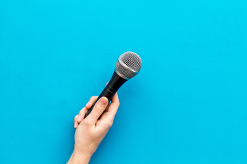 blogger, journalist or musician work space with microphone in hand on blue background top view space for text