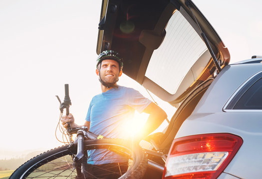 Man taking his bicycle out from the trunk of a car