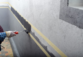 female painting a wall with masking tape and roller