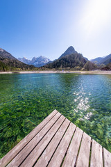 Wooden dock on lake Jasna with mountains Razor and Prisojnik