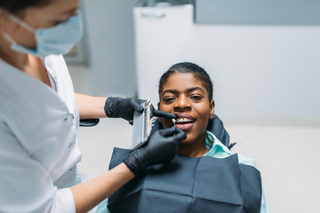 Female dentist choosing the shade of teeth