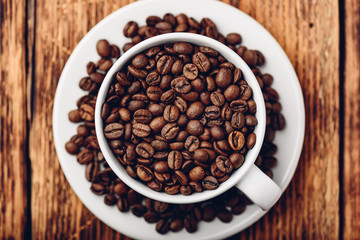 White cup full of roasted coffee beans
