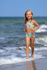 Little girl in swimsuit running on the beach