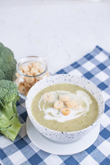 Cream soup puree with broccoli, cream and crackers. Lunch of vegetables on a light background. Plate and napkin on the table