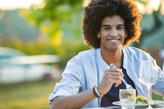 Portrait of smiling afro young man having food outdoors