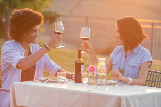 Couple raising wine glass while sitting at table outdoors