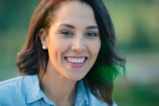 Portrait of smiling young woman with black hair standing outdoors