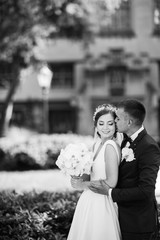 Elegant bride in a white dress and veil. Handsome groom in a blue suit. Couple in a summer park