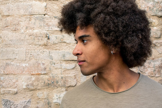 Close up of afro young man standing against brick wall