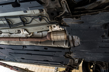 The exhaust system in the car seen from below, the car is on the lift in the car workshop.