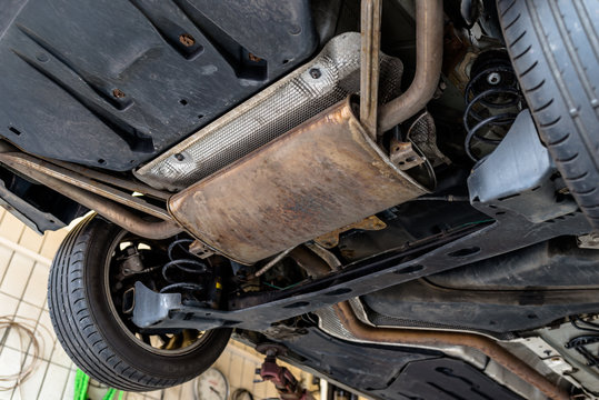 The exhaust system in the car seen from below, the car is on the lift in the car workshop.